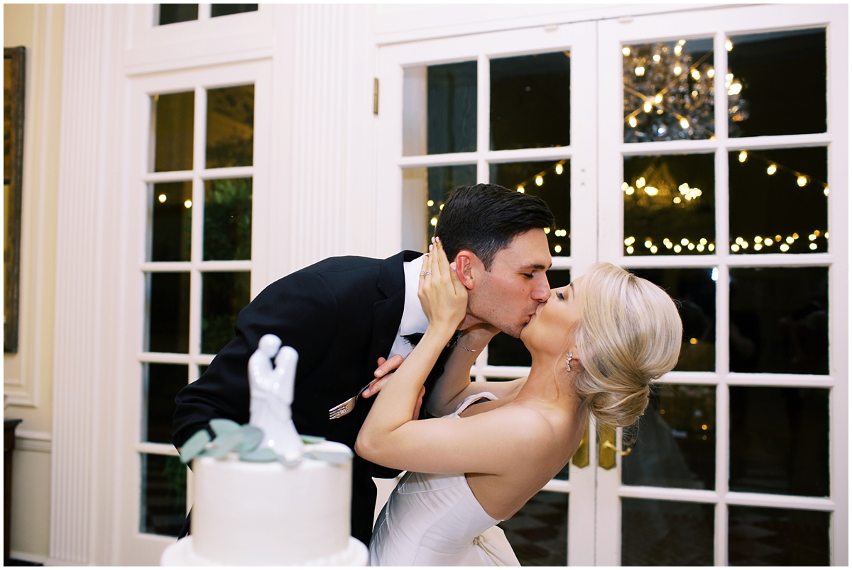 bride and groom kiss after cutting cake at Duke Mansion wedding reception
