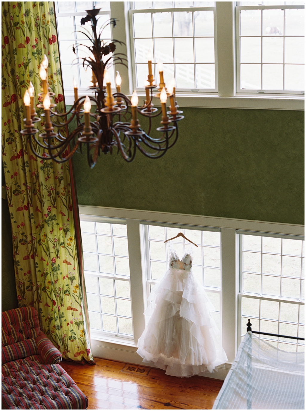 A modern low cut tulle wedding ballgown hanging in the window at Marblegate Farm house.