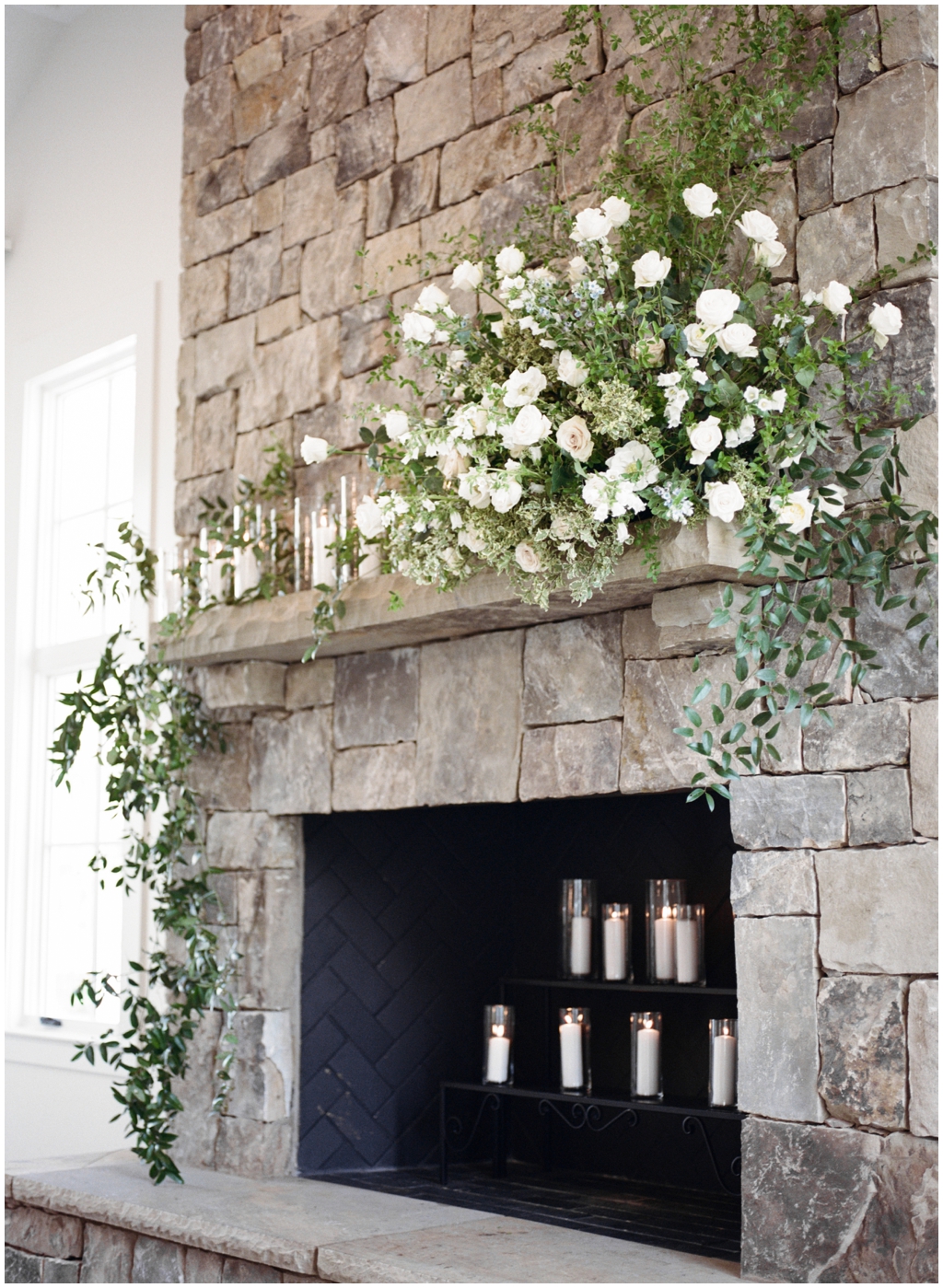 Indoor stone fireplace draped in Thistle and Lace rose florals at Marblegate Farm