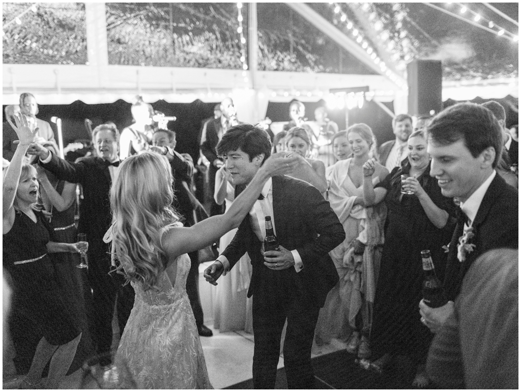 Classic black and white image of bride and groom dancing with guests in the middle of the dance floor