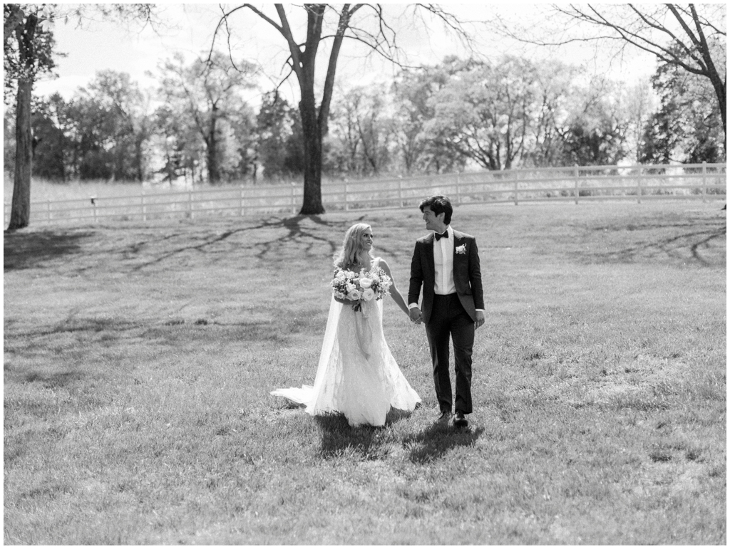 Bride and groom walk across the meadow at Marblegate Farm wedding venue