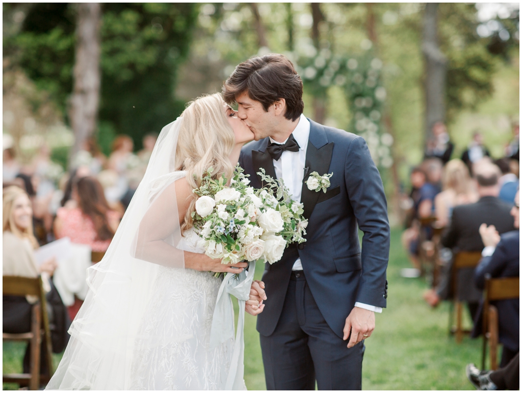 Bride and groom share a kiss at the end of the aisle 