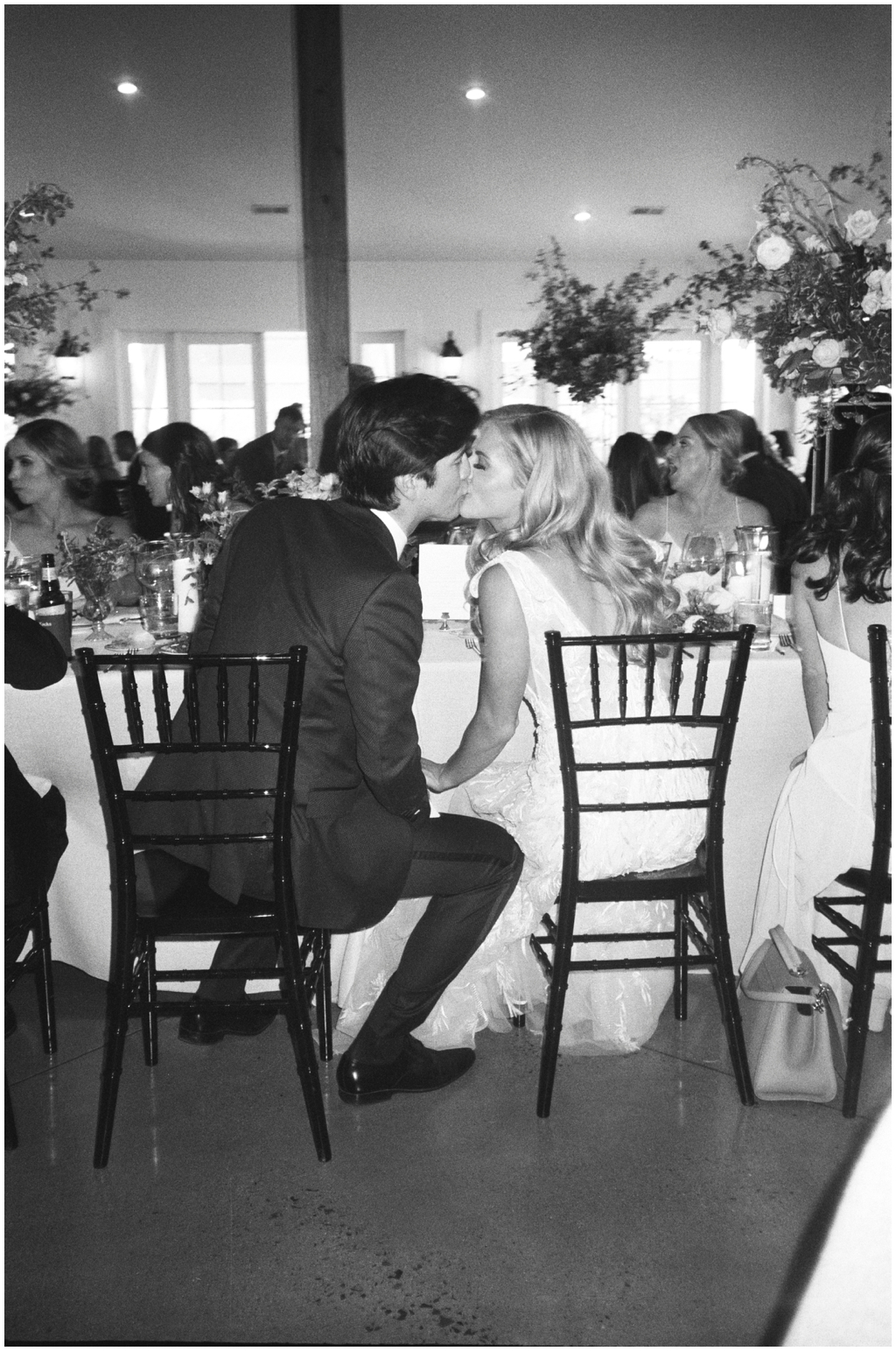 Bride and groom share a kiss at head table during the dinner