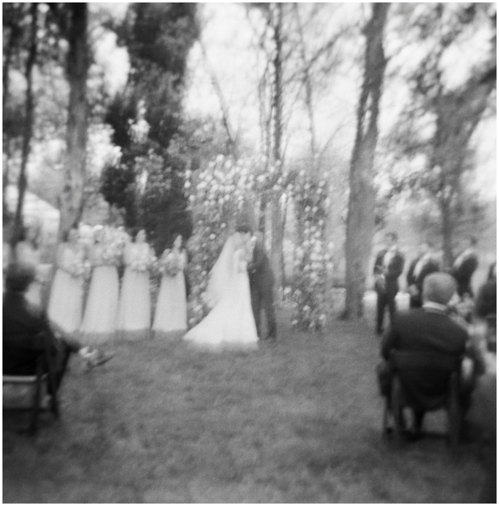 Black and white film image of the bride and groom kissing at outdoor spring ceremony at Marblegate Farm.